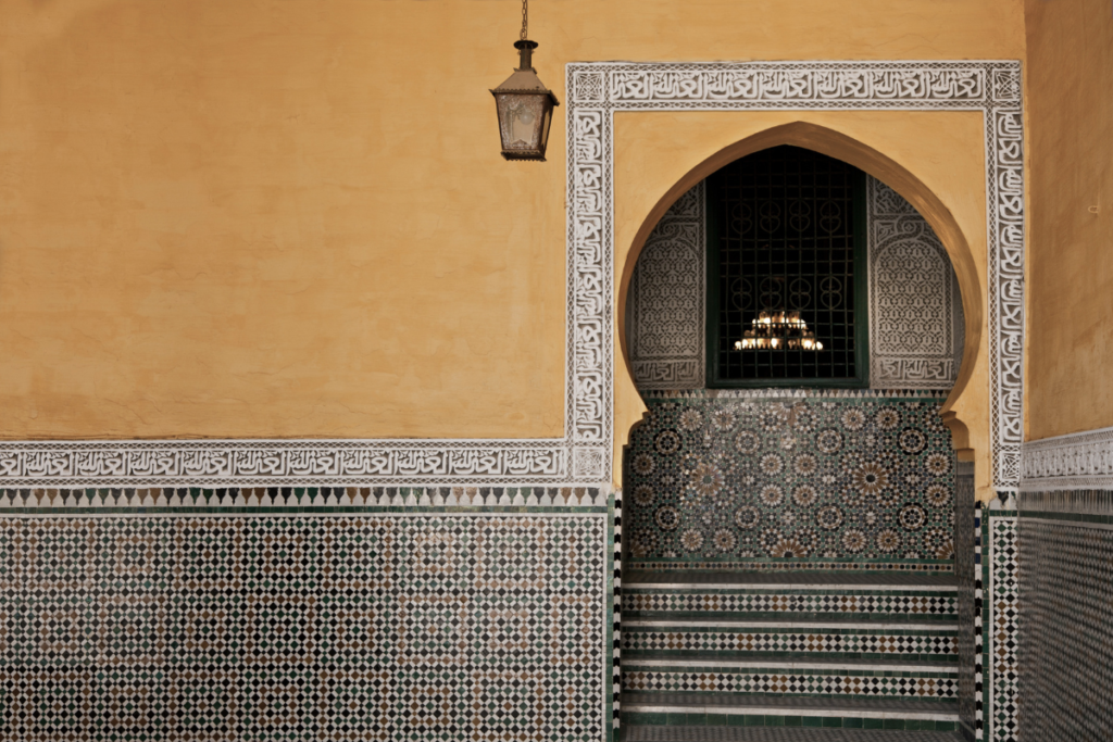 Traditional Moroccan doorway framed by intricate tilework and geometric patterns, representing anticipation, discovery, and cultural travel. Meknes, Morocco