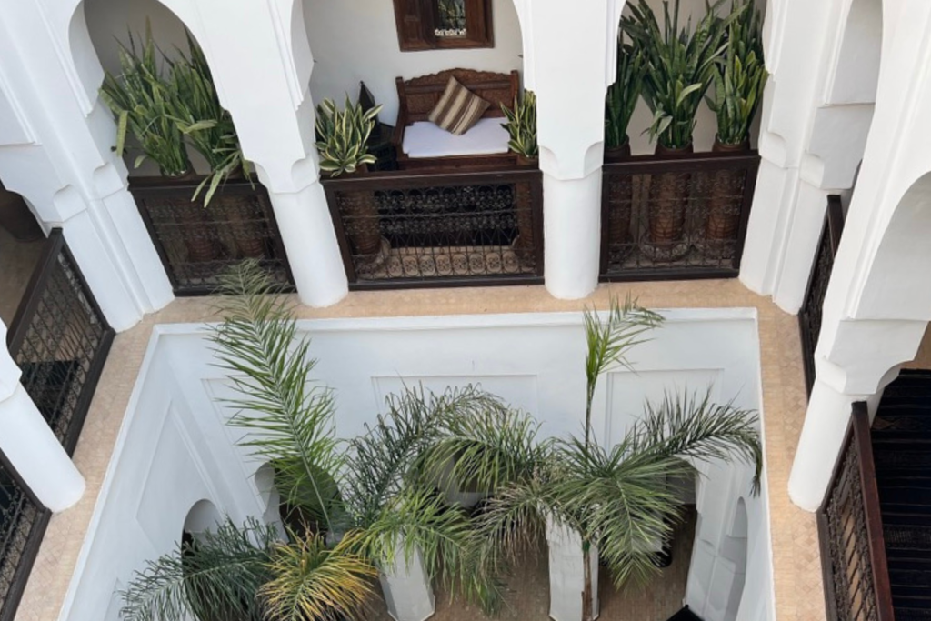 Traditional Moroccan riad interior courtyard with palm trees and white walls