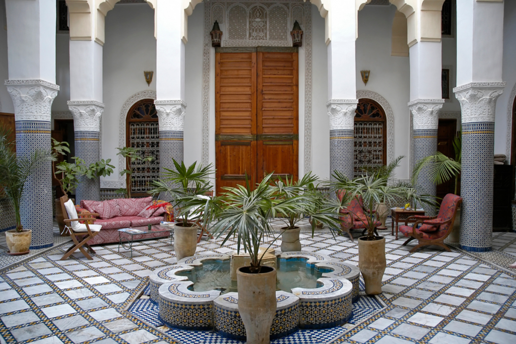Traditional Moroccan riad courtyard with fountain, mosaic floors and carved columns