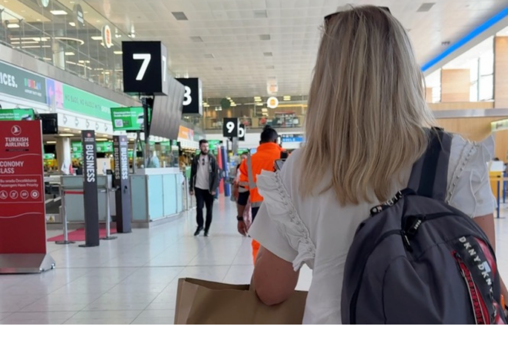 Woman walking through an airport terminal with a backpack